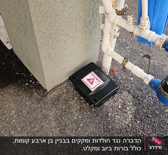 קופסת הדברה שחורה עם סימן אזהרה על הקרקע